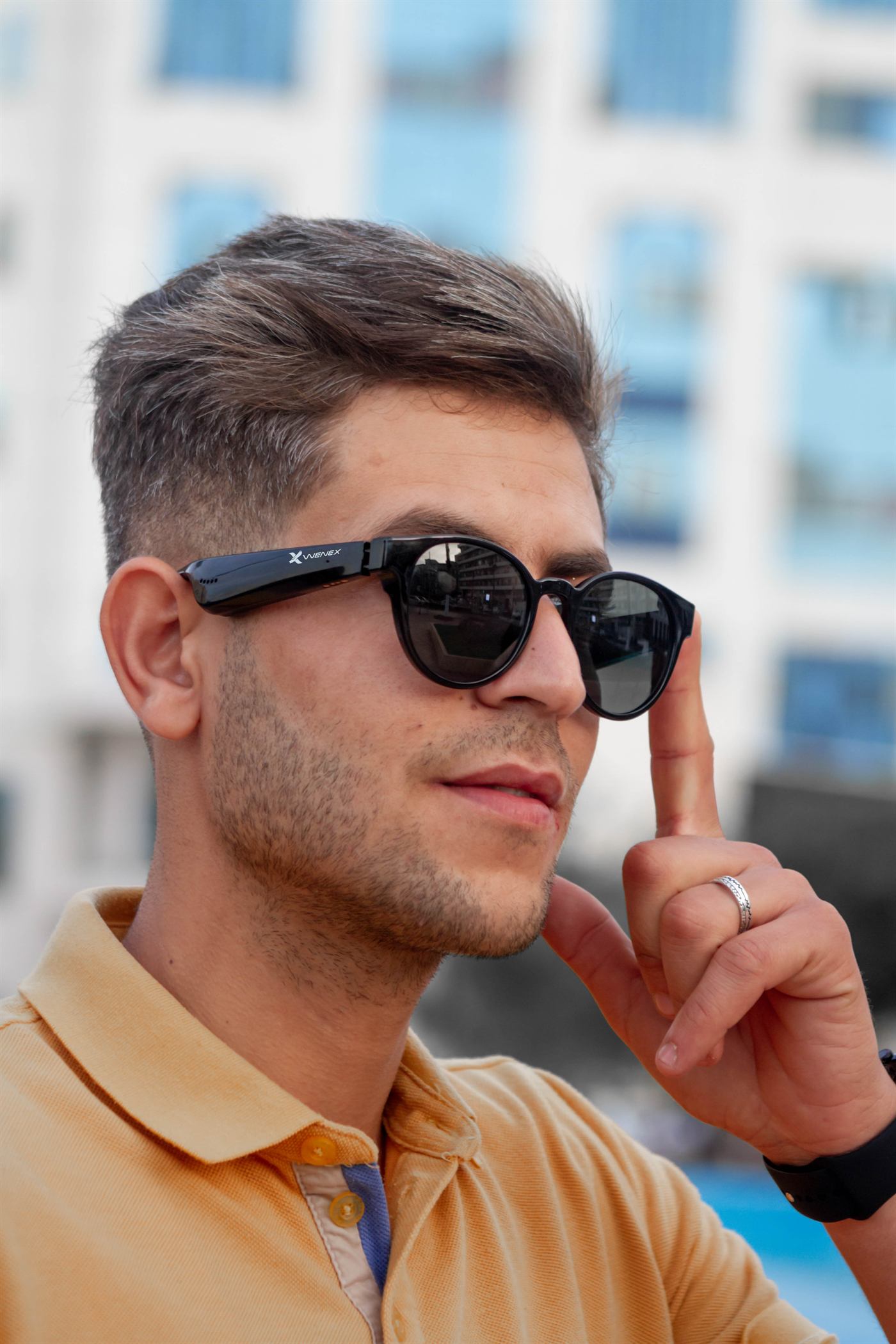 A creator on a city street wearing WENEX ViaVel glasses, looking past the camera.
