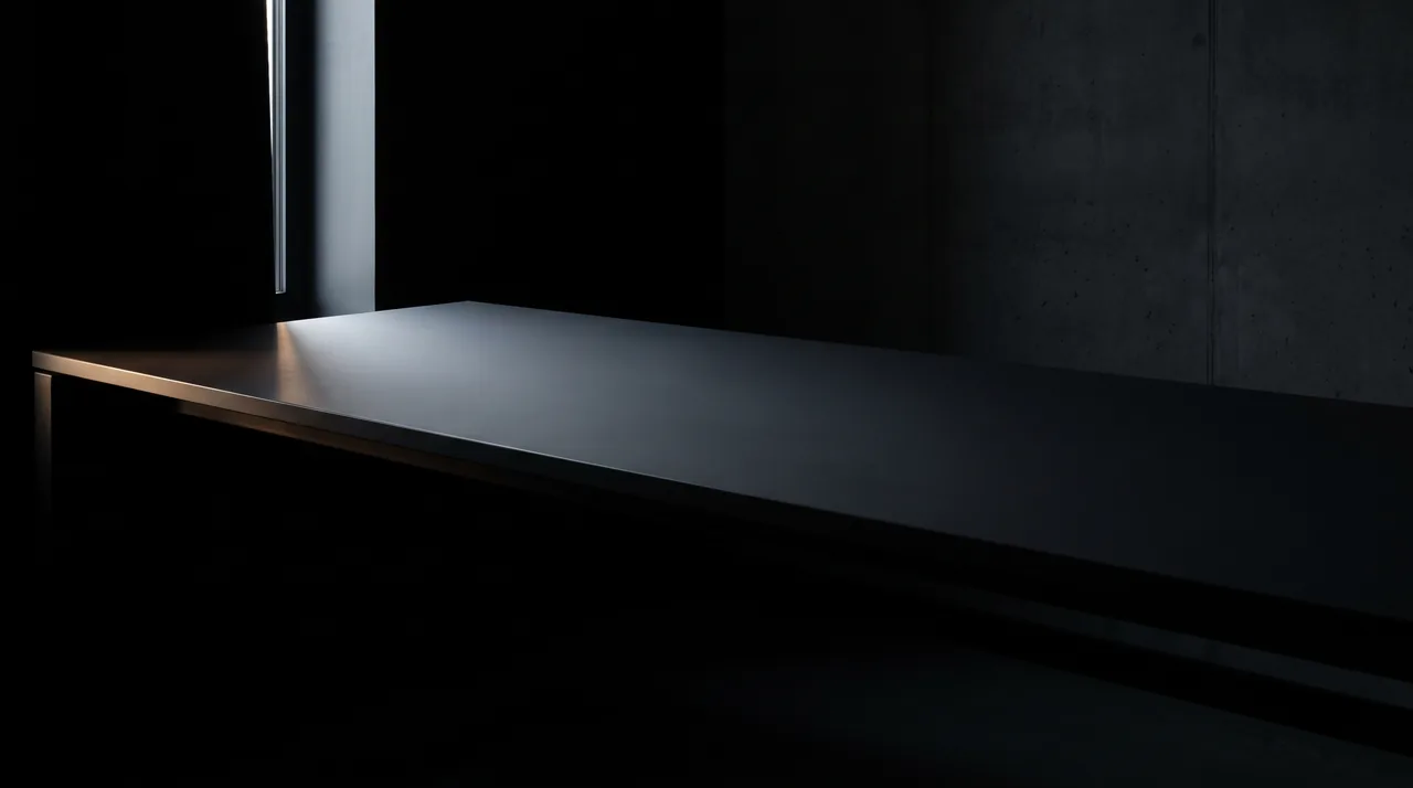 An empty desk in a dark room, lit by a single narrow band of light